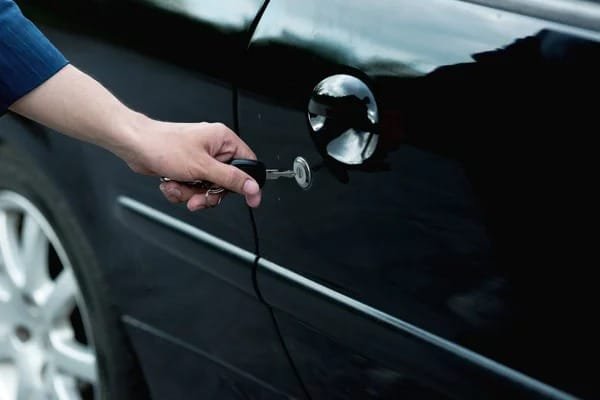 a person hand on car door latch and find Ways to Improve Car Security