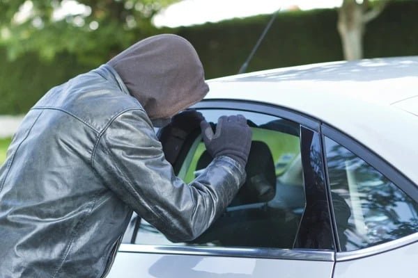 hooded thief looking through car window